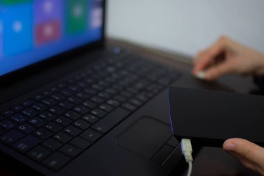 Laptop 'a kablo bağlarken harici sabit disk tutan kadın