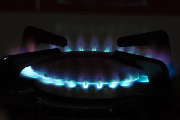 Gas burner with blue flame, glowing fire ring on kitchen stove. Modern kitchen with natural gas cooking