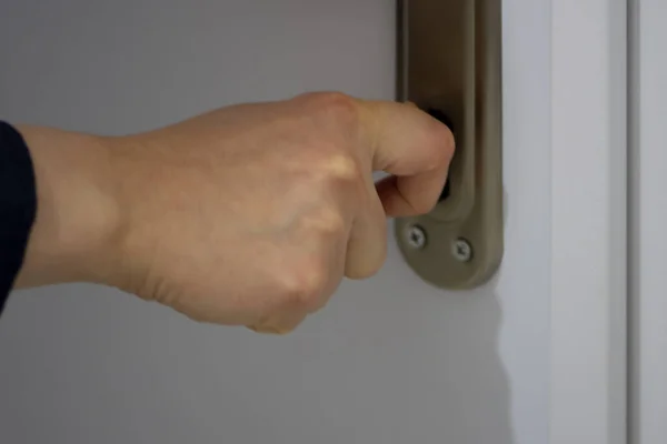 Close up of womans right hand locking or unlocking the white door