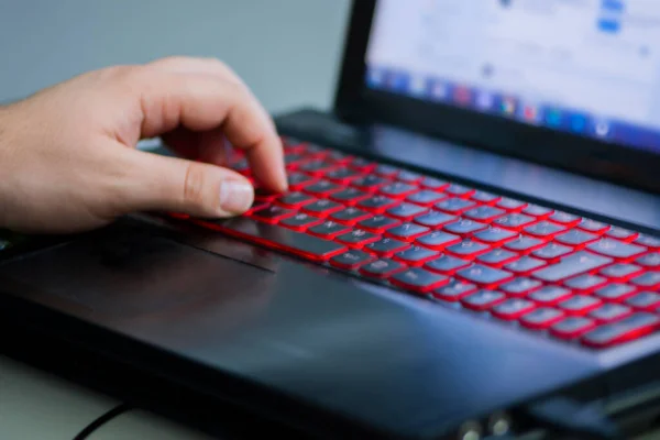 Mans mano izquierda en el teclado iluminado portátil Imagen de archivo