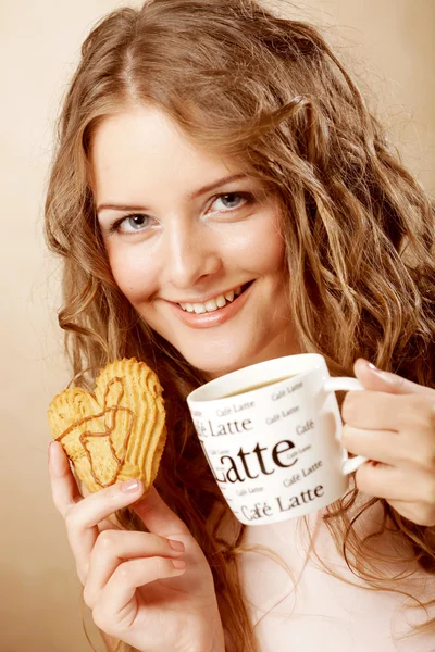 Woman eating cookie and drinking coffee. — Stock fotografie