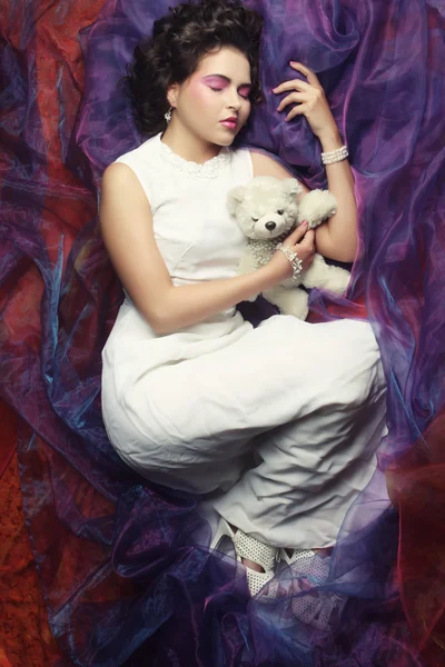 Woman lay on organza with teddy bear — Stock Photo, Image