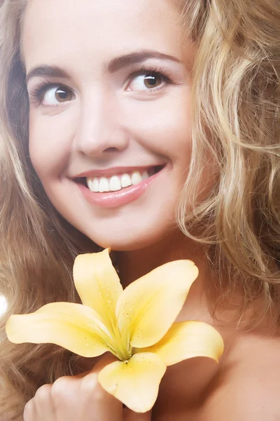 Young girl with yellow lily laughs Royalty Free Stock Images