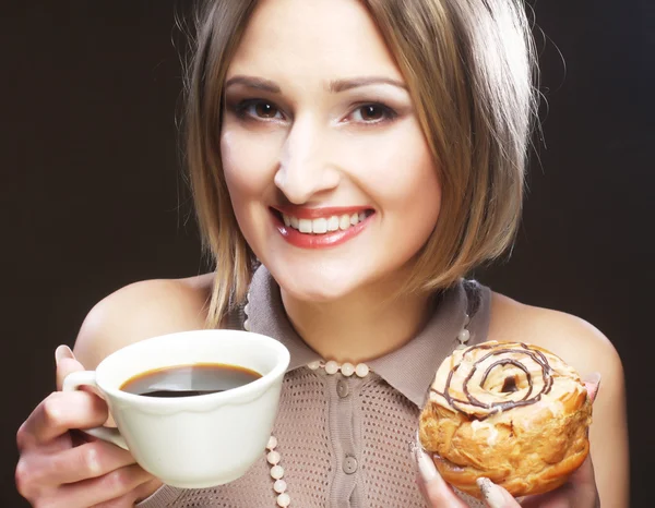 Woman eating cookie and drinking coffee. — Stockfoto