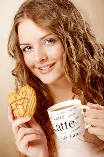 Woman eating cookie and drinking coffee. — Stock fotografie