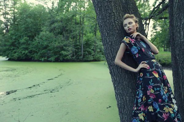 Jeune femme posant sur un arbre — Photo