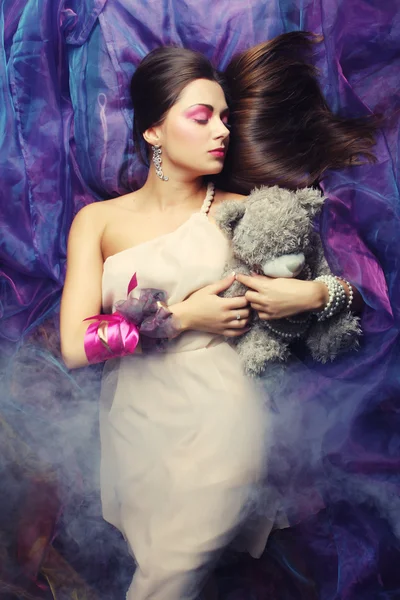 Woman lay on organza with teddy bear — Stock Photo, Image