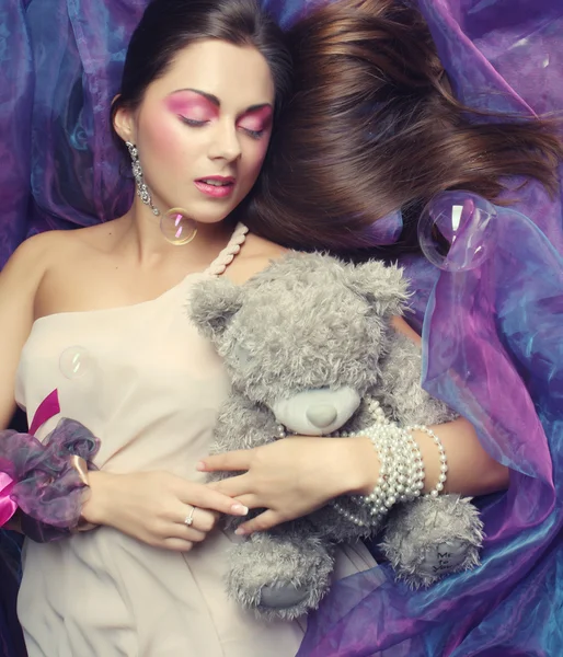 Woman lay on organza with teddy bear — Stock Photo, Image