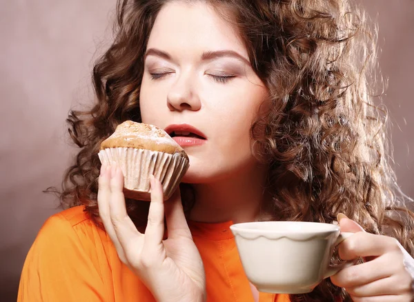 Woman eating cookie and drinking coffee. — Stockfoto