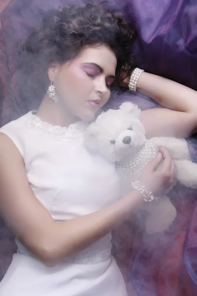 Woman lay on organza with teddy bear — Stock Photo, Image