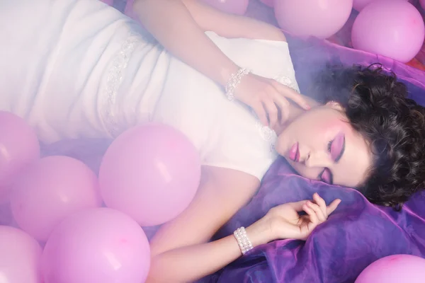 Mujer durmiendo acostada en el suelo entre globos — Foto de Stock
