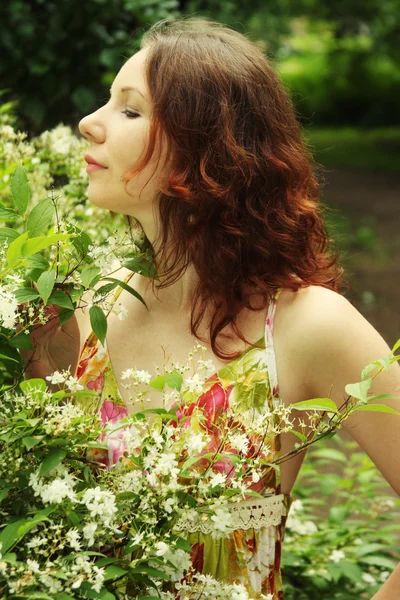 Kvinna med blommor som poserar i sommaren park — Stockfoto