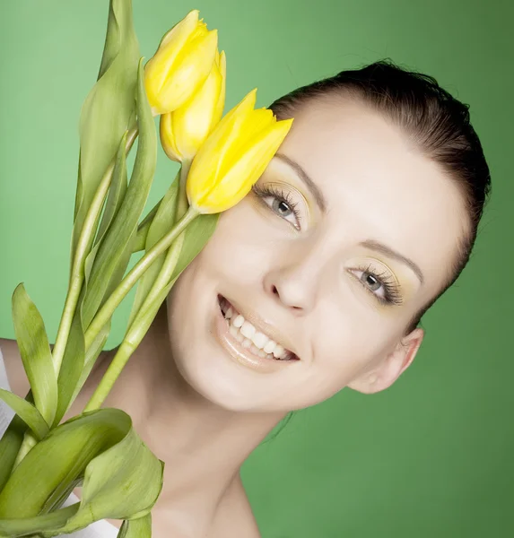 Mulher com tulipas amarelas sobre fundo verde — Fotografia de Stock
