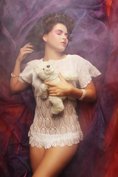 Woman lay on organza with teddy bear — Stock Photo, Image