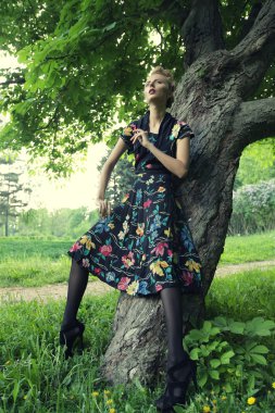 Genç bir kadın ağaçta poz veriyor.