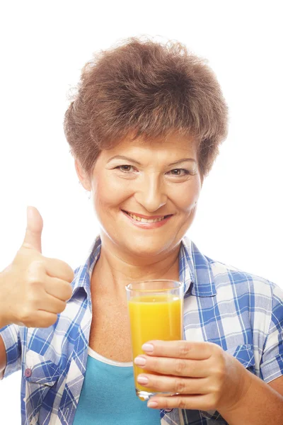 Mulher madura segurando um copo de suco de laranja — Fotografia de Stock