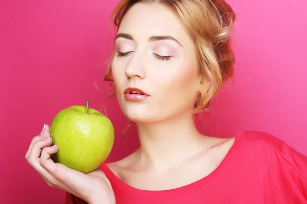 Kvinna med apple över rosa bakgrund — Stockfoto
