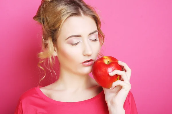 Kvinna med apple över rosa bakgrund — Stockfoto