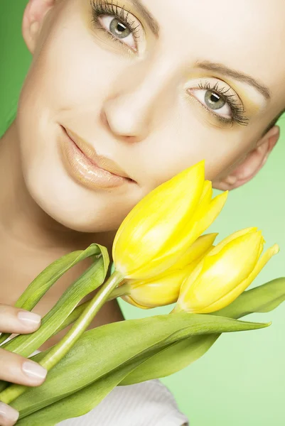 Frau mit gelben Tulpen auf grünem Hintergrund — Stockfoto