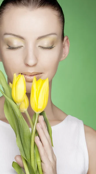 Mujer con tulipanes amarillos sobre fondo verde — Foto de Stock