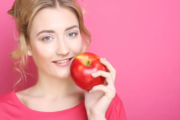 Mujer con manzana sobre fondo rosa — Foto de Stock