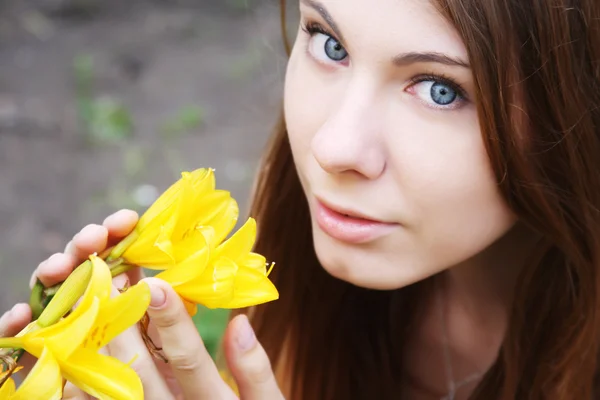 Kvinna med blommor som poserar i sommaren park — Stockfoto