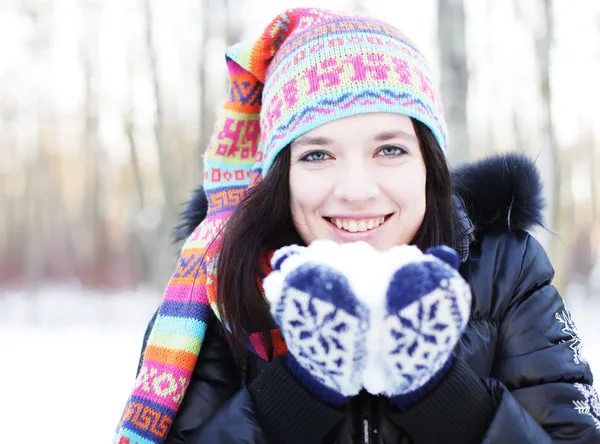 Donna nel parco invernale, soffia la neve giocosamente — Foto Stock