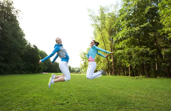 Two young girls jump in summer park. — Stock Photo, Image