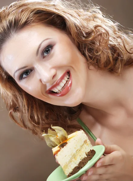Mujer joven sosteniendo un delicioso pedazo de pastel — Foto de Stock