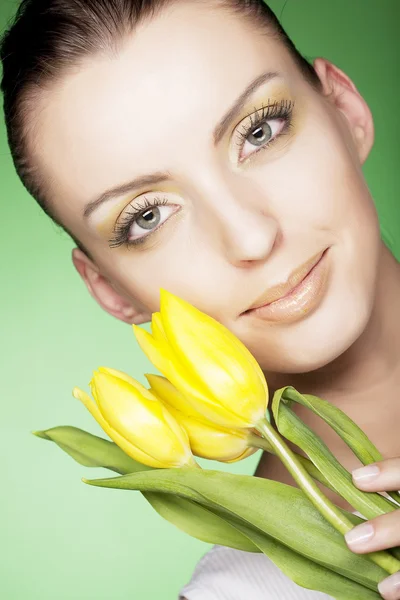 Vrouw met gele tulpen op groene achtergrond — Stockfoto