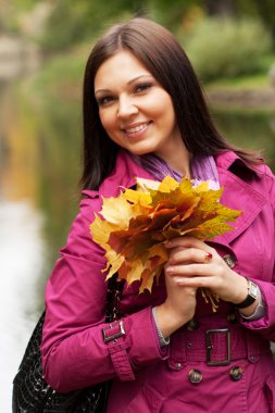 Parkta sonbahar yapraklı genç bir kadın