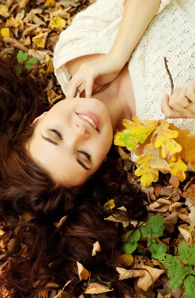 Mujer acostada sobre hojas de otoño, retrato al aire libre —  Fotos de Stock