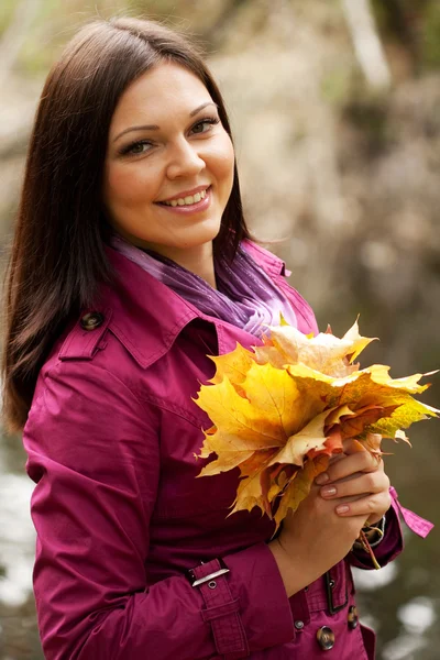 Young woman with autumn leaves in park — Stock Photo, Image