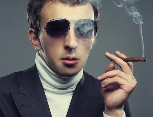 Muž nosí sluneční brýle a kouření cigerette. — Stock fotografie