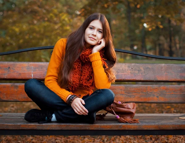 Chica en el banco en el parque de otoño — Foto de Stock