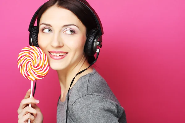 Beautiful woman with headphones and candy — Stock Photo, Image