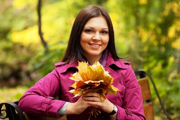 Giovane donna elegante con foglie d'autunno — Foto Stock