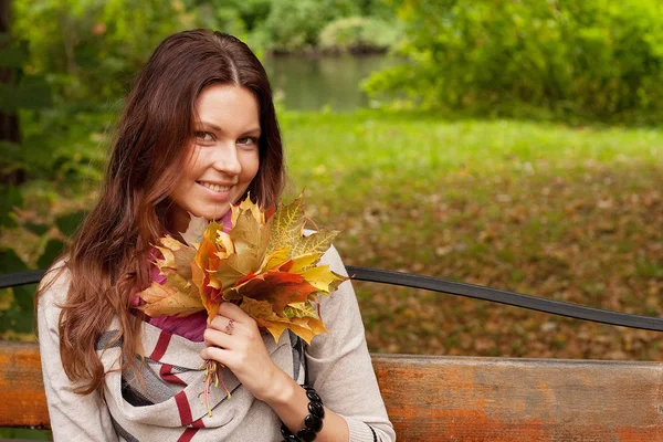 Giovane donna elegante con foglie d'autunno — Foto Stock