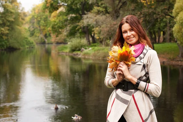 Mujer joven con hojas de otoño en el parque —  Fotos de Stock