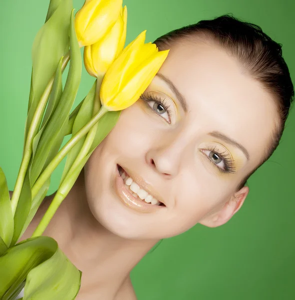 Kobieta z żółtych kwiatów na zielonym tle — Zdjęcie stockowe