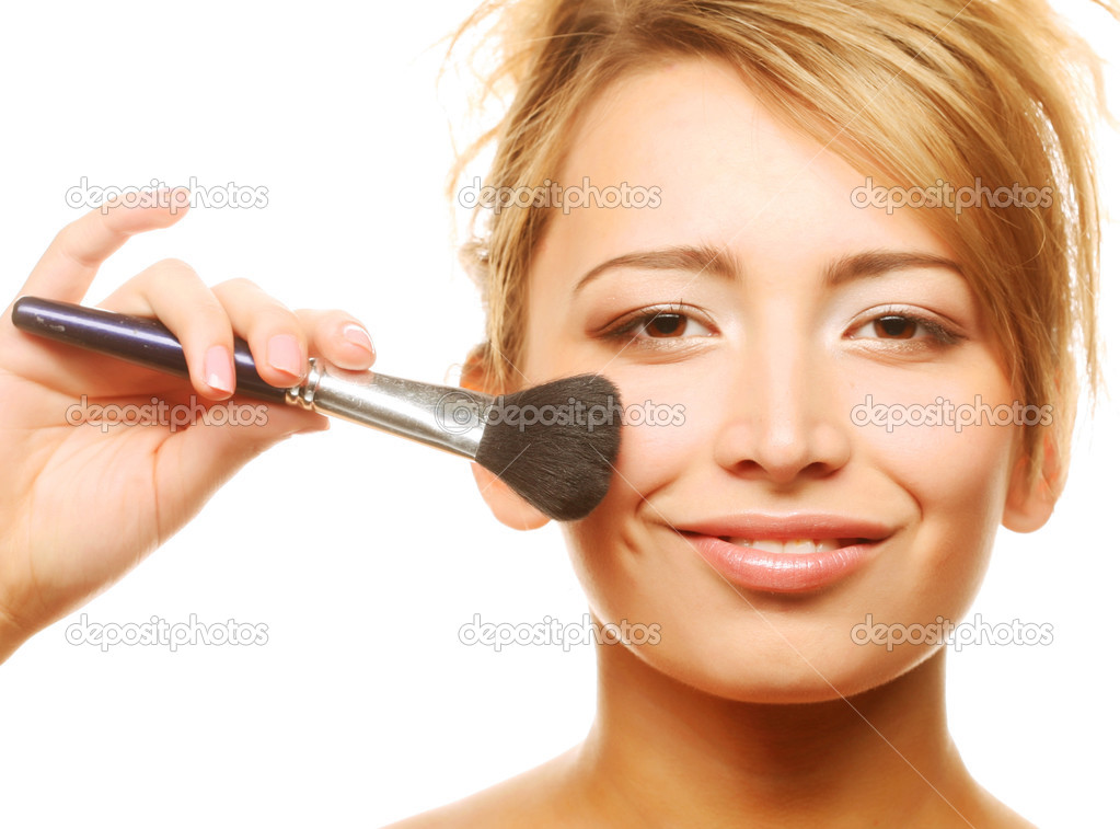 Attractive young adult woman applying blusher