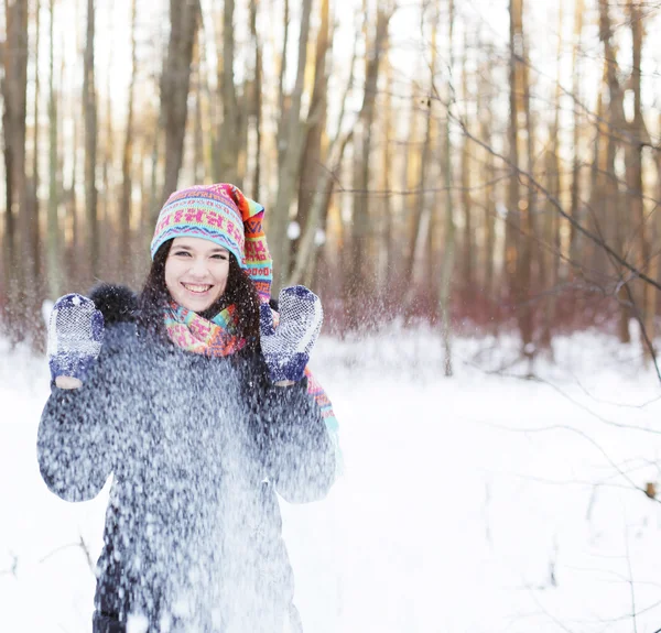 Женщина в зимнем парке, весело дующая в снег — стоковое фото