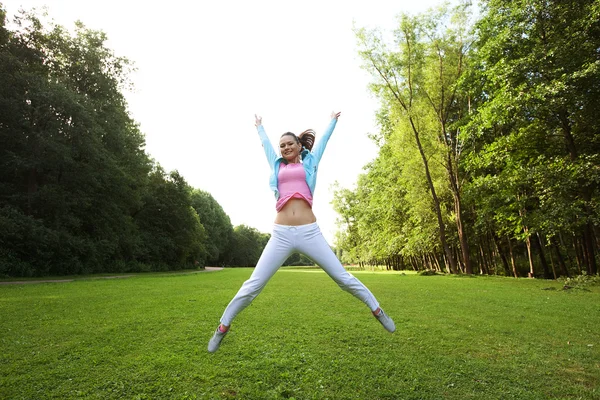 Jonge vrouw springen op groen gras — Stockfoto