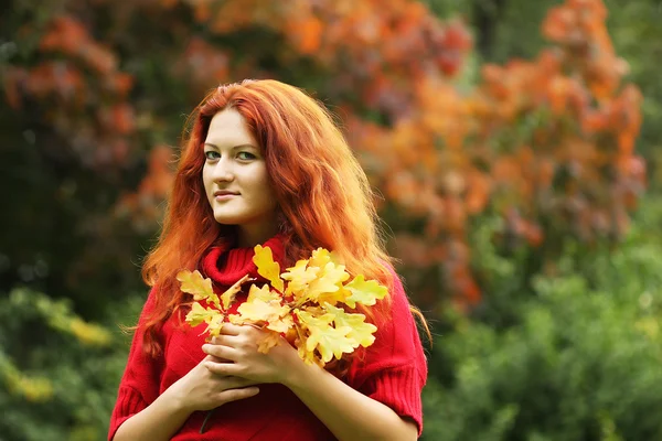 Jeune femme avec des feuilles d'automne dans le parc — Photo