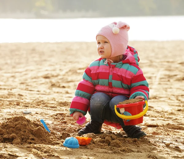 Dziewczynka gra z piasku na plaży jesień — Zdjęcie stockowe