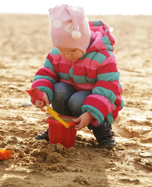 Kum ile sonbahar sahilde oynarken küçük kız — Stok fotoğraf