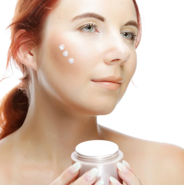 Young smiling woman applying cream on her face — Stock Photo, Image