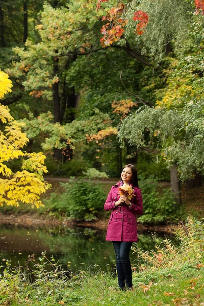 在公园里放秋叶的年轻女子 — 图库照片