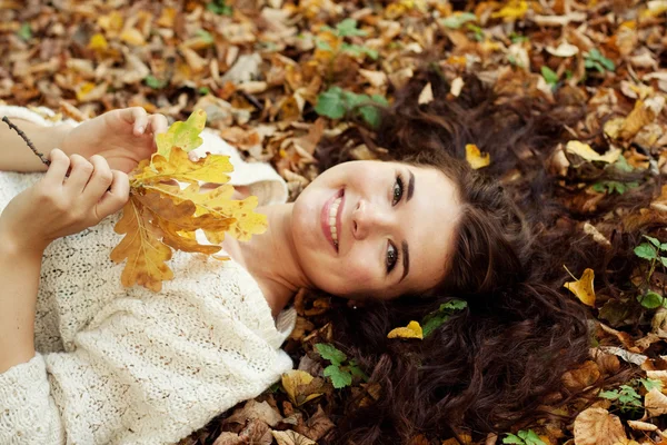 Donna sdraiata sulle foglie autunnali, ritratto all'aperto — Foto Stock
