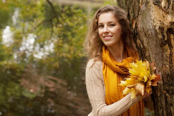 Giovane donna sorridente nel parco d'autunno — Foto Stock